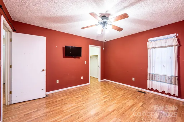 a view of a livingroom with a chandelier fan and wooden floor