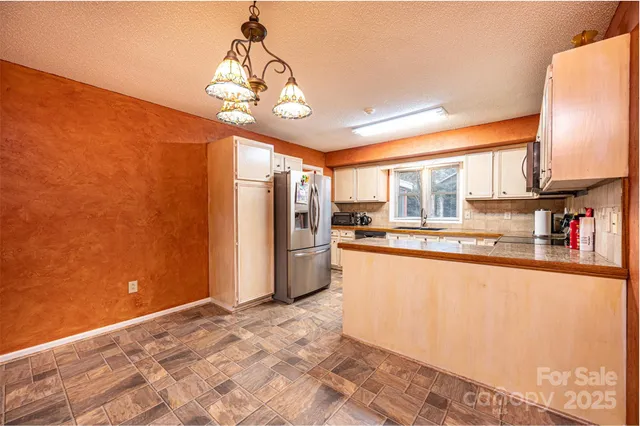 a kitchen with stainless steel appliances granite countertop a refrigerator a sink dishwasher a stove and white cabinets with wooden floor