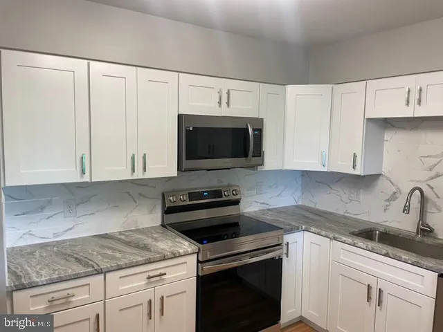 a kitchen with granite countertop white cabinets and stainless steel appliances