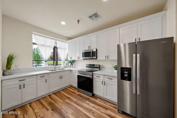 a kitchen with granite countertop white cabinets and stainless steel appliances