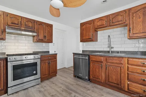 a kitchen with granite countertop a sink cabinets and stainless steel appliances
