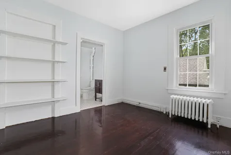 a view of an empty room with a window and wooden floor