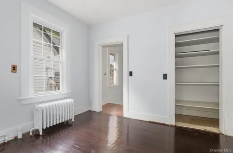 a view of an empty room with wooden floor and windows