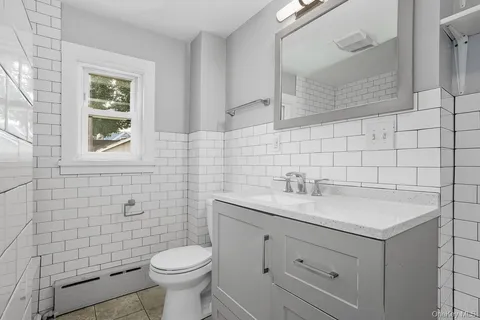 a bathroom with a granite countertop toilet a sink a mirror and a shower