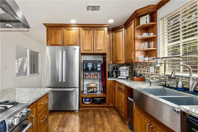 a kitchen with granite countertop a refrigerator a sink dishwasher stove and wooden cabinets