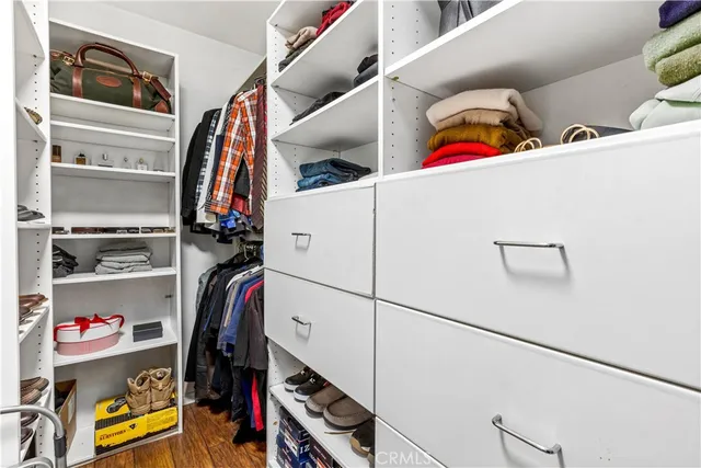 a view of walk in closet with clothes and shoes
