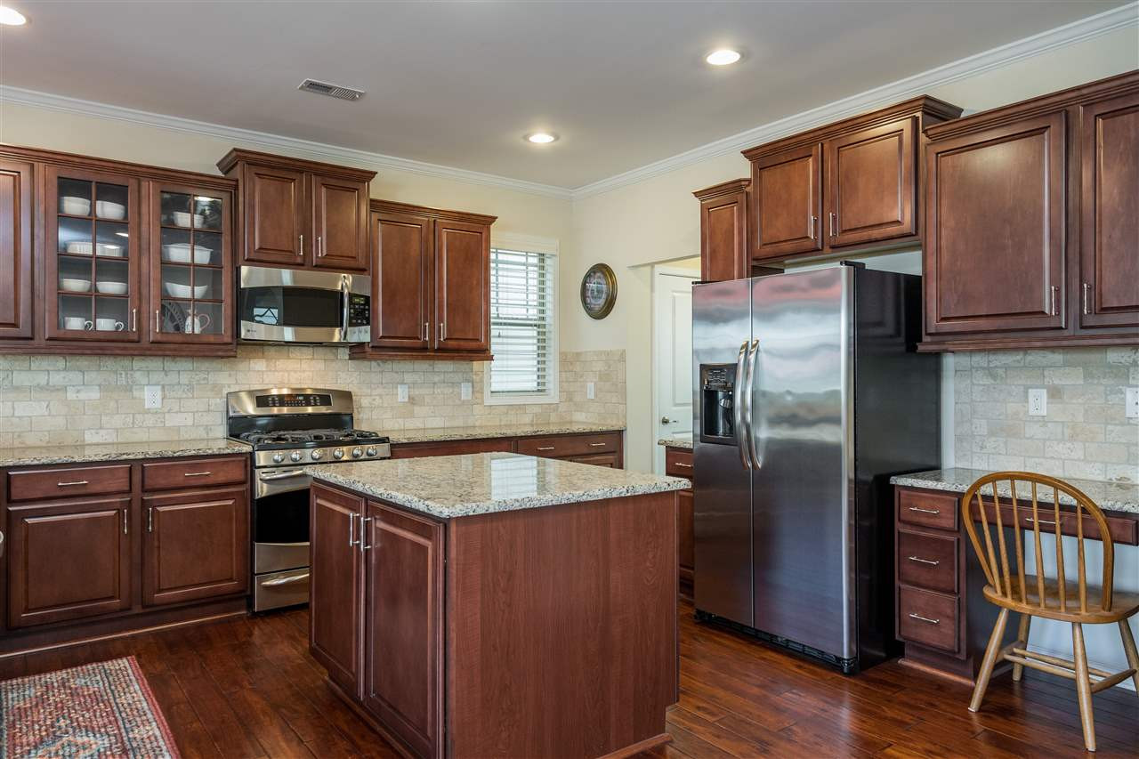 This kitchen has it all! Open concept, island, working desk, granite, subway tile, stainless appliances, included refrigerator, glass front cabinet and recessed can lighting! Kitchen