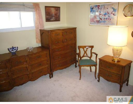 23 Kenmore Road Edison, NJ 08817 - Photo 7 of 8 a bedroom with a bed and a lamp on dresser