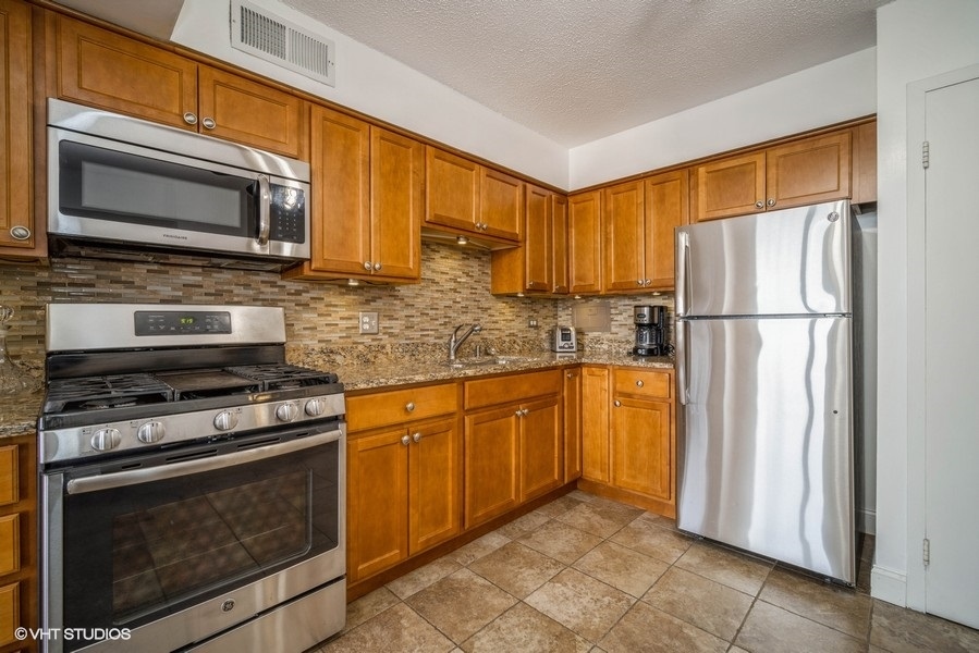 8801 West Golf Road, Unit 10E Niles, IL 60714 - Photo 13 of 21 a kitchen with stainless steel appliances granite countertop a refrigerator stove and microwave