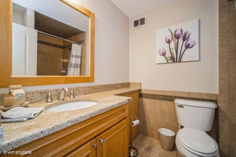 8801 West Golf Road, Unit 10E Niles, IL 60714 - Photo 14 of 21 a bathroom with a granite countertop toilet sink and mirror