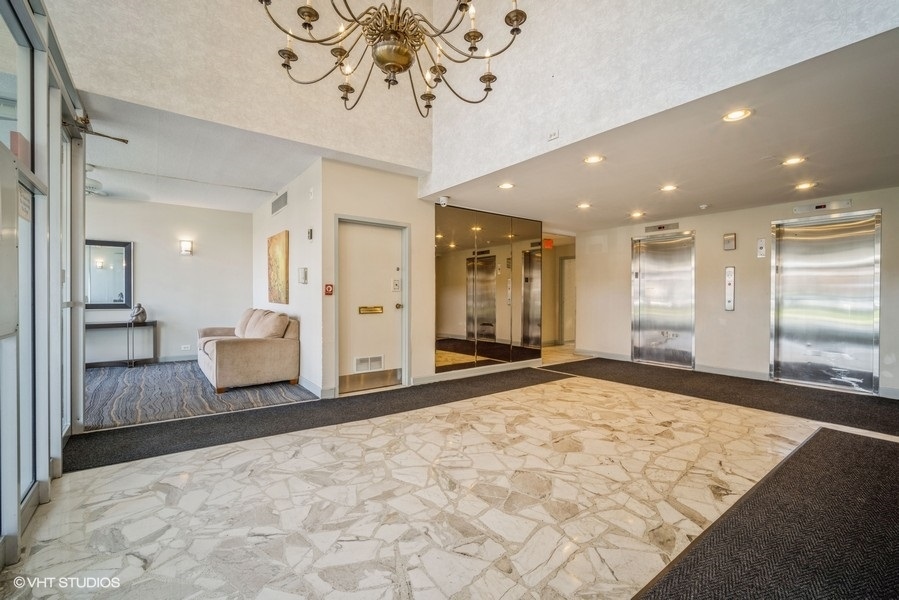 8801 West Golf Road, Unit 10E Niles, IL 60714 - Photo 2 of 21 a view of a hallway with wooden floor and a chandelier