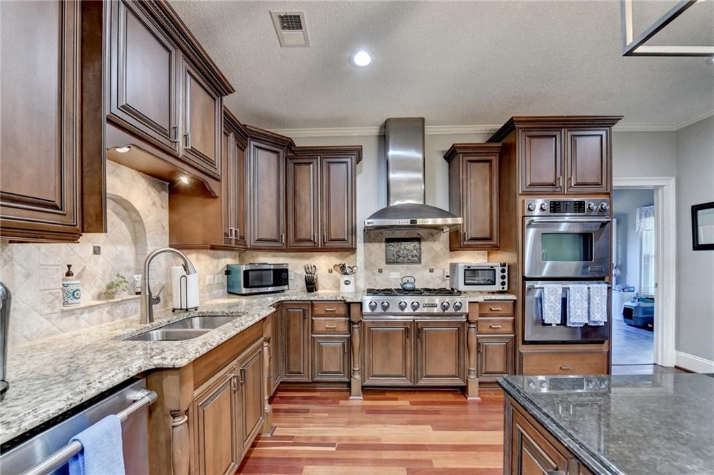 4420 Benefield Road Braselton, GA 30517 - Photo 17 of 34 a kitchen with stainless steel appliances granite countertop a stove top oven a sink dishwasher and cabinets with wooden floor