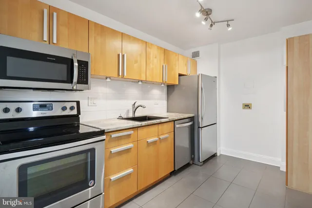 a kitchen with stainless steel appliances granite countertop a stove microwave refrigerator and cabinets