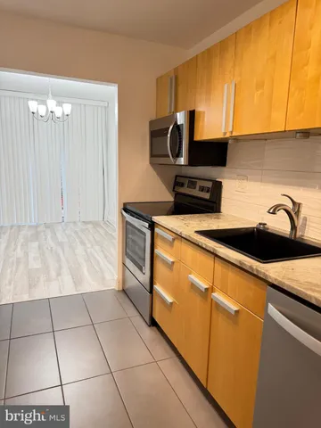 a kitchen with stainless steel appliances a sink a stove top oven a counter space and cabinets