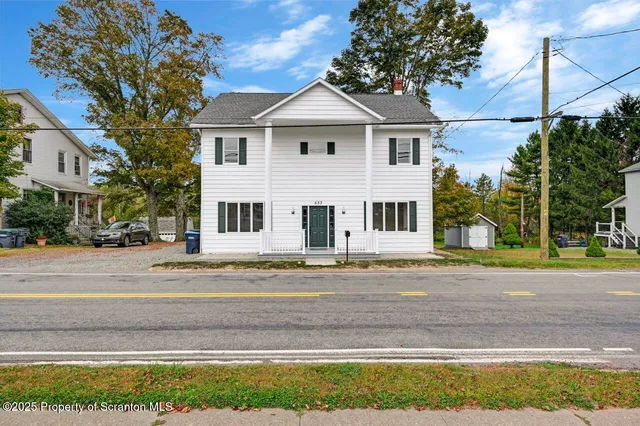 a front view of a house with a yard and large trees