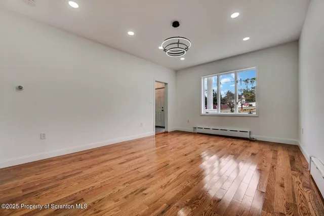 a view of empty room with wooden floor and windows