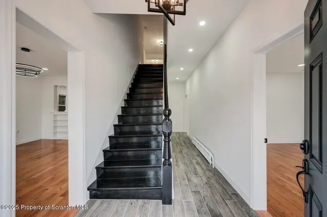 a view of an empty room with window and wooden floor