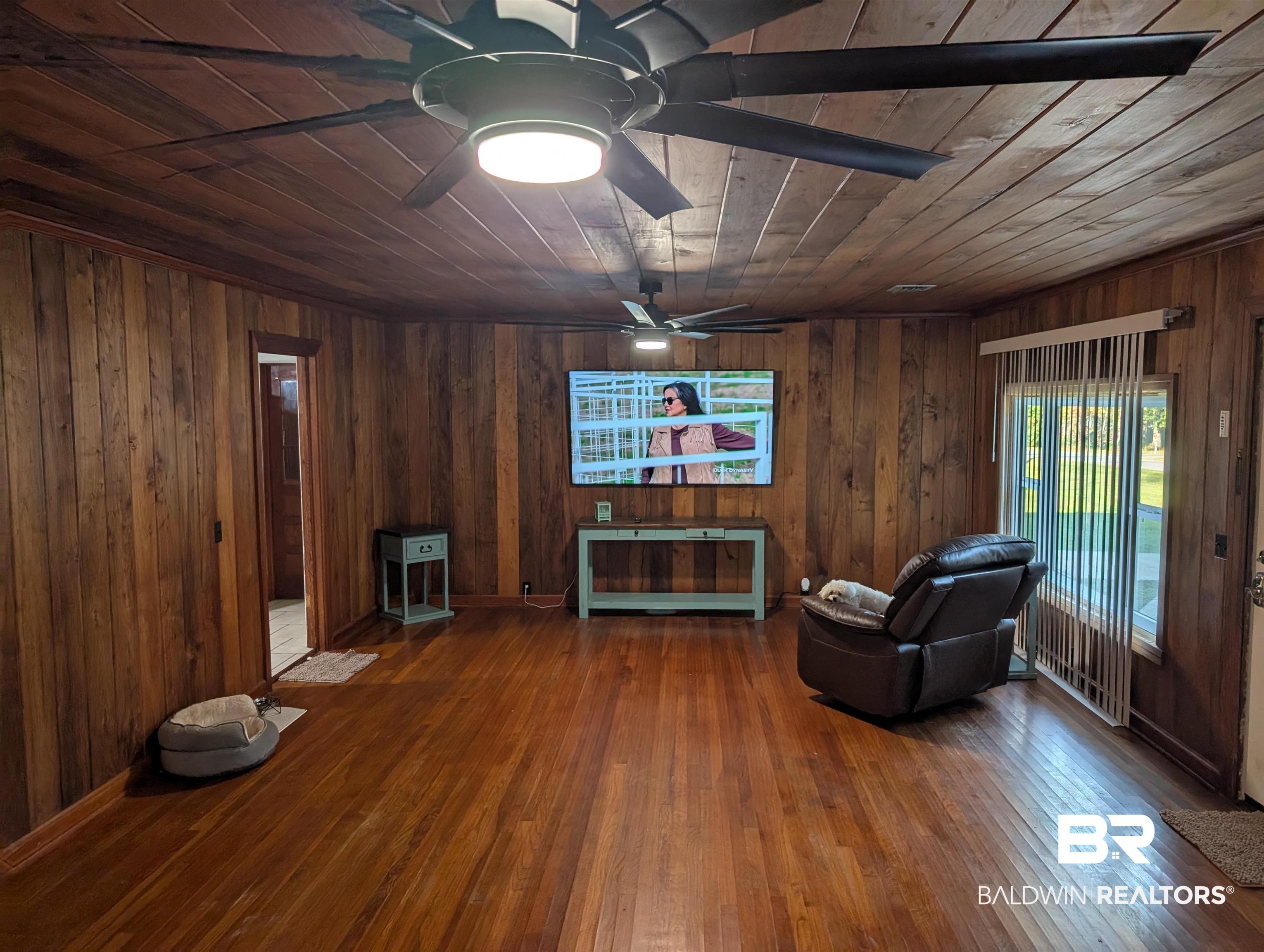 22103 2nd Street Silverhill, AL 36576 - Photo 9 of 10 Living area with wooden ceiling, wood-type flooring, and wooden walls