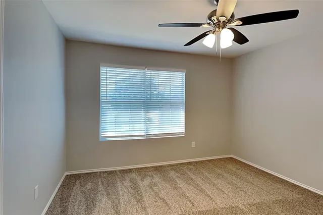 an empty room with a window and a fan