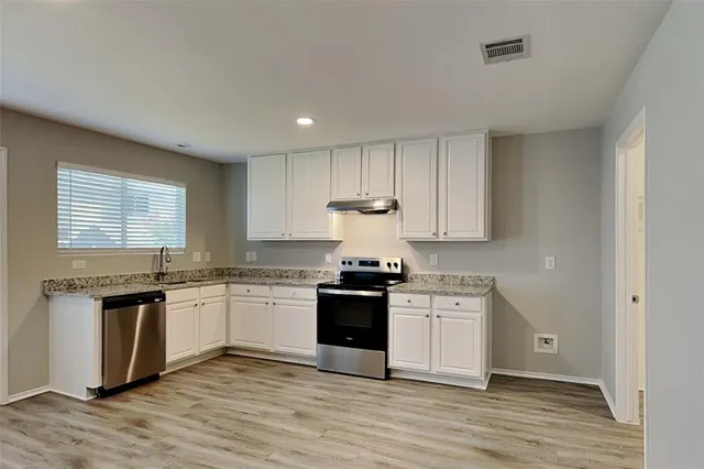 a kitchen with stainless steel appliances granite countertop a stove and white cabinets