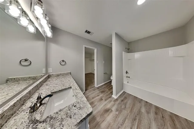 a spacious bathroom with a granite countertop sink a mirror and shower