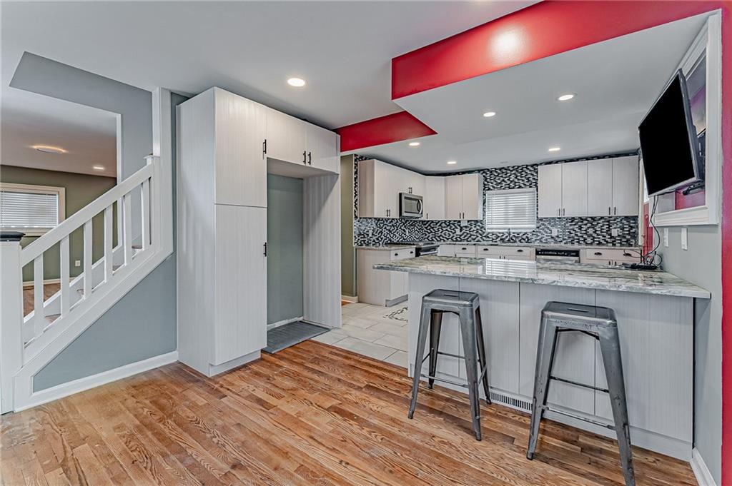 414 Hochberg Road Pittsburgh, PA 15235 - Photo 18 of 23 a kitchen with stainless steel appliances granite countertop a refrigerator a stove a sink dishwasher and white cabinets with wooden floor