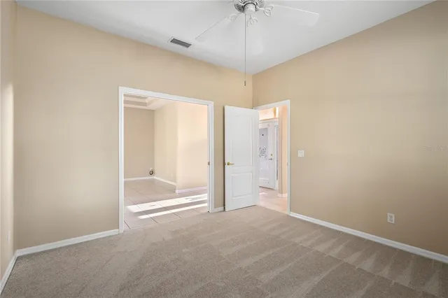 an empty room with a chandelier fan and a bathroom