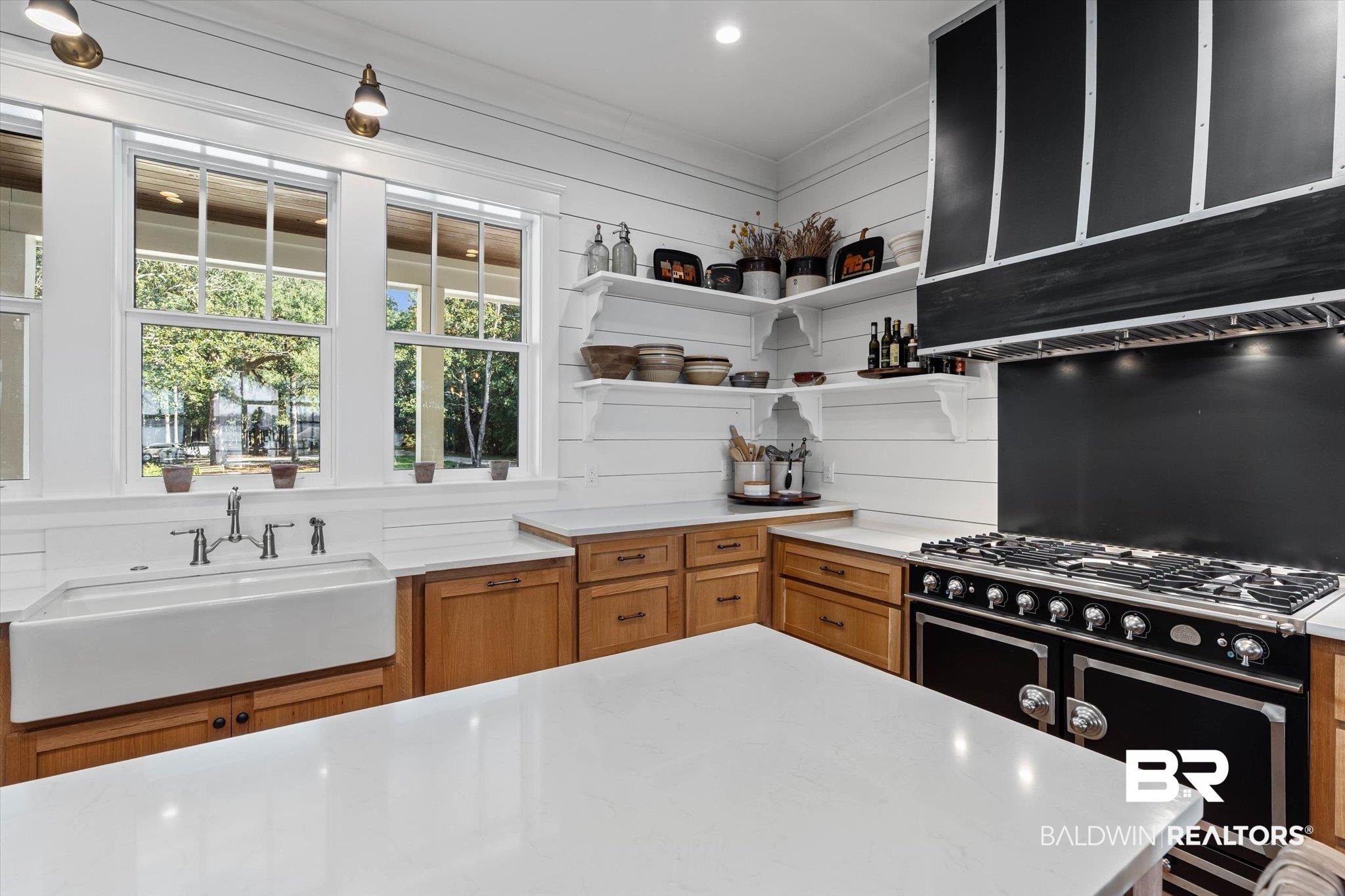 2415 Venetia Road Mobile, AL 36605 - Photo 12 of 50 Kitchen featuring brown cabinetry, high end black range, custom exhaust hood, light stone countertops, and open shelves