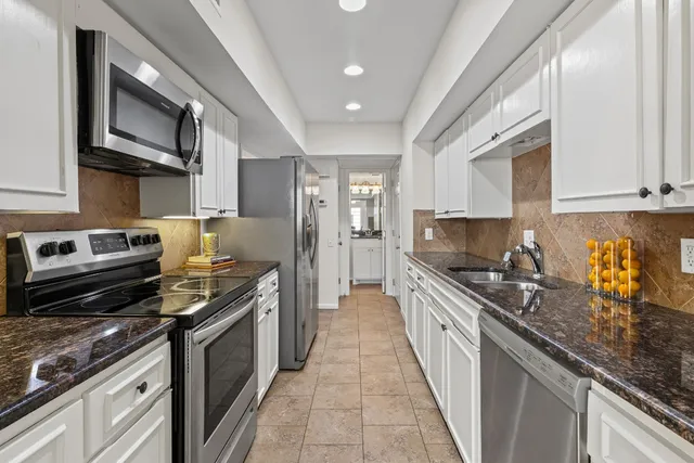 a kitchen with stainless steel appliances granite countertop a stove a sink and a microwave