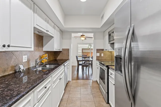 a kitchen with stainless steel appliances granite countertop a refrigerator a stove and a sink