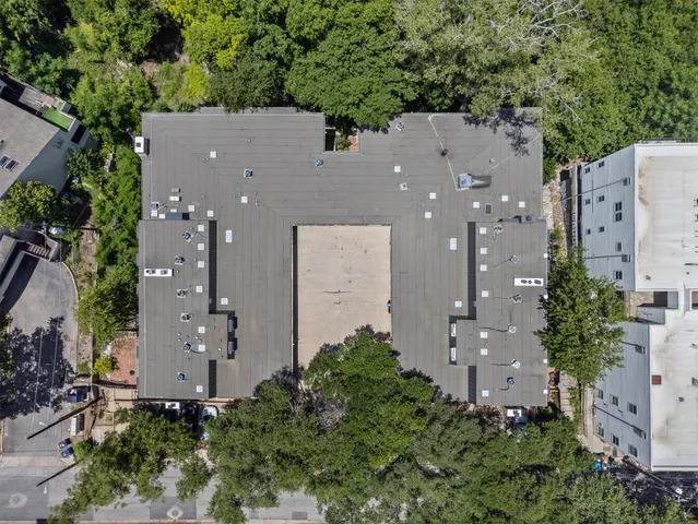 an aerial view of a house with outdoor space and trees all around