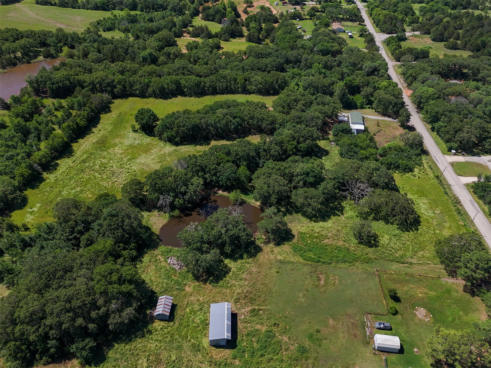 0 Harvey Road Ardmore, OK 73401 - Photo 8 of 10 Extensive acreage featuring a visible pond, mature trees, open grassy areas, and a paved road frontage