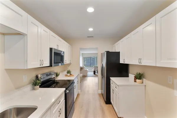 a kitchen with stainless steel appliances a refrigerator sink and white cabinets