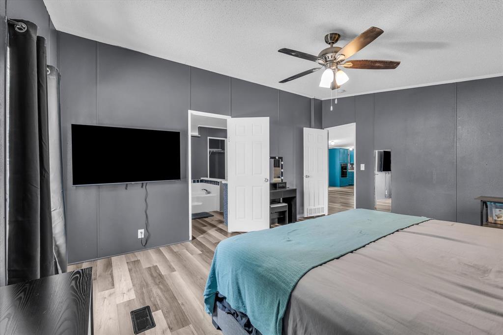 3615 Spring Valley Road Lorena, TX 76655 - Photo 25 of 33 Bedroom featuring wood-finish flooring, a ceiling fan with light fixture, and dark gray paneling