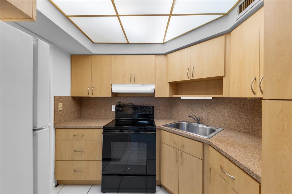2151 Northeast 42nd Court, Unit 230 Lighthouse Point, FL 33064 - Photo 5 of 40 a kitchen with a refrigerator and a sink