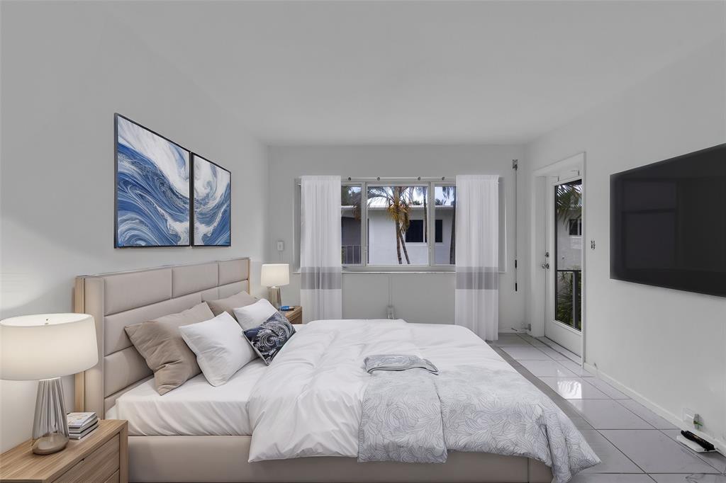 2151 Northeast 42nd Court, Unit 230 Lighthouse Point, FL 33064 - Photo 7 of 40 a bedroom with a large bed and a flat screen tv