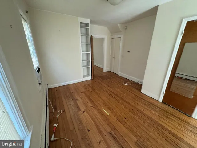 a view of an empty room with wooden floor and stairs