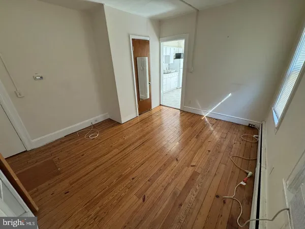 a view of an empty room with wooden floor and closet