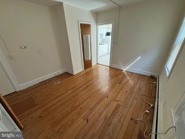 a view of an empty room with wooden floor and closet