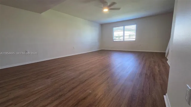 a view of an empty room with wooden floor and stairs