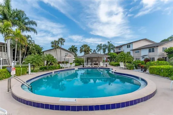 a small pool with lawn chairs and plants