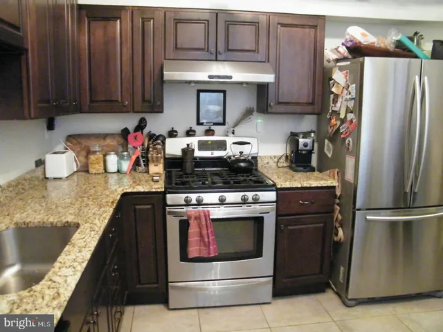 a kitchen with stainless steel appliances granite countertop a refrigerator stove and sink