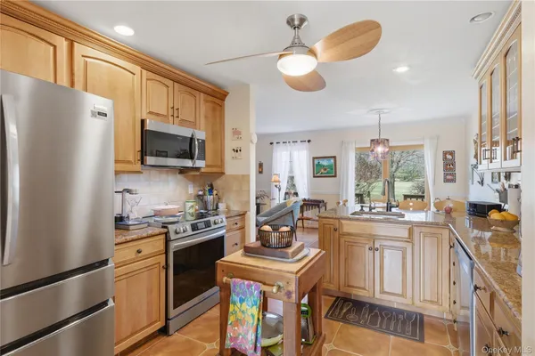 a kitchen with stainless steel appliances granite countertop a stove top oven a refrigerator a sink and dishwasher with wooden floor