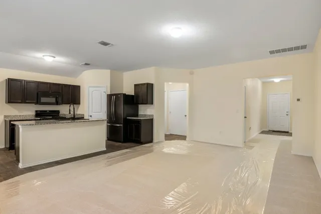 a large white kitchen with kitchen island a counter top space a sink stainless steel appliances and cabinets