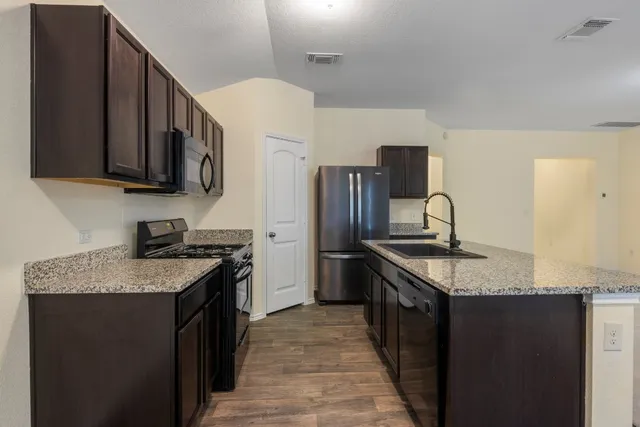 a kitchen with stainless steel appliances granite countertop a stove microwave and sink