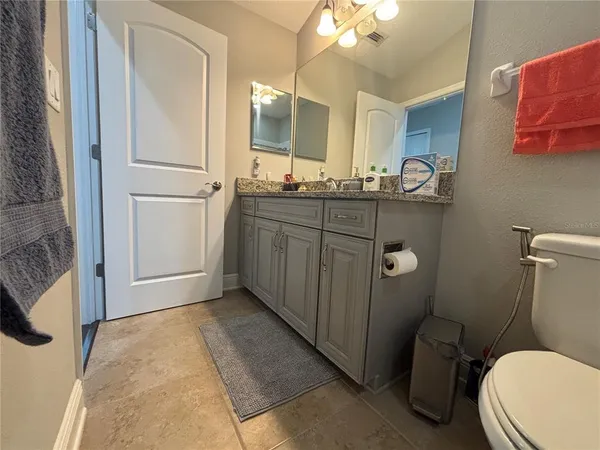 a bathroom with a granite countertop toilet sink and mirror