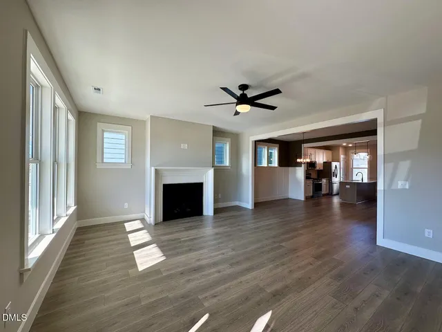 an empty room with wooden floor fireplace and windows