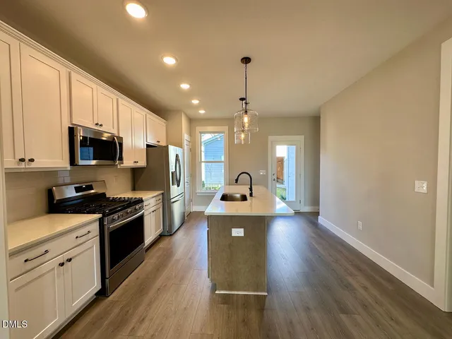 a kitchen with stainless steel appliances a refrigerator a sink a stove and white cabinets