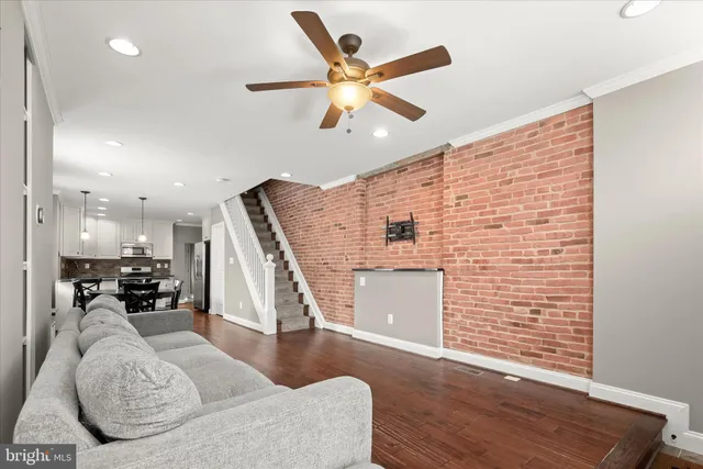 a view of a livingroom with a ceiling fan & windows