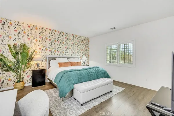 a spacious bedroom with a bed and wooden floor